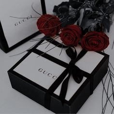 two black and white boxes with red roses in them