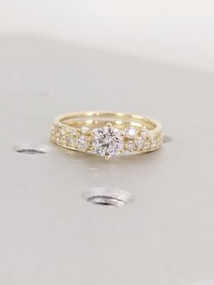 a yellow gold engagement ring with three diamonds on the top and bottom, sitting on a white surface