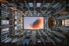 the view from below looking up at a building with many windows and clouds in the sky