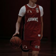 a young man holding a basketball on top of a gym floor in red and white