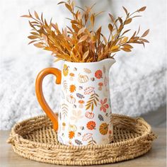 a coffee mug with leaves on it sitting on a wicker tray