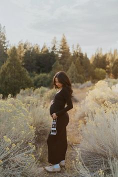 a pregnant woman standing in the middle of a field