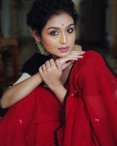 a woman in red sari posing for a photo with her hands on her chest