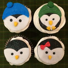 four cupcakes with frosting decorated like penguins