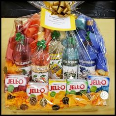 a gift basket filled with assorted liquor bottles and candies, wrapped in cellophane