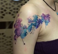 a woman's shoulder with watercolor tattoos on it