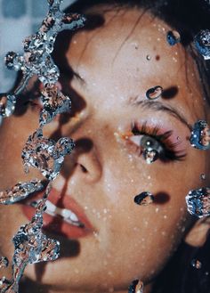 a woman with lots of water on her face and eyeliners covered in crystals