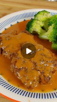 a plate topped with meat covered in gravy and broccoli