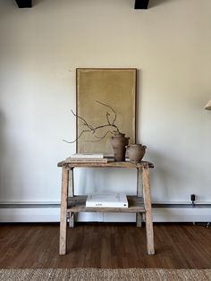 a wooden table sitting in front of a painting on the wall next to a lamp