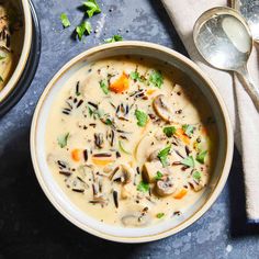 two bowls of mushroom soup with spoons next to each other on a blue surface