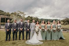 a group of people standing next to each other in front of a field with trees