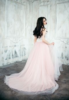 a woman in a long pink dress is standing with her back turned to the camera