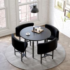 a round table with four chairs around it in front of a window and a rug on the floor