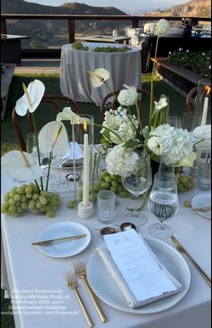 the table is set with white flowers and silverware