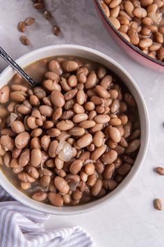 two bowls filled with beans on top of a table