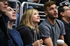 several people sitting in the stands at an ice hockey game, one is looking up