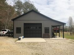 a two car garage sits in the middle of a gravel lot next to a white pickup truck