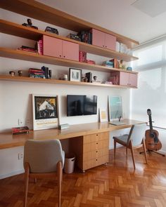 a desk with two chairs and a guitar on it in front of a wall mounted tv