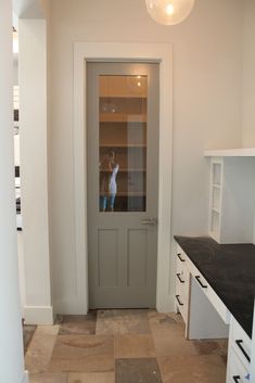 an empty kitchen with white cabinets and black counter tops in front of a gray door