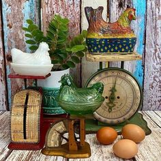 an assortment of old fashioned clocks and other items on a wooden table with painted wood boards in the background