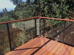 a wooden deck with metal railing and trees in the background