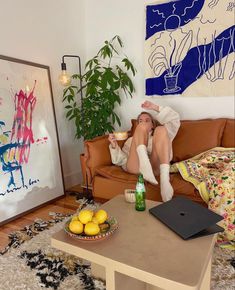 a woman sitting on top of a brown couch next to a table filled with lemons