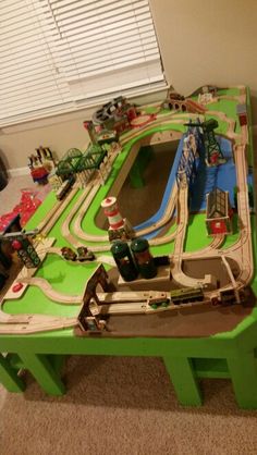 a green table with a toy train set on top of it in the living room