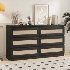 a black and white dresser sitting on top of a hard wood floor next to a potted plant