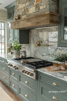 a kitchen with green cabinets and marble counter tops, gold knobs on the hood