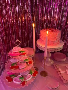 a table topped with lots of cakes and cupcakes next to a candle on top of a cake plate