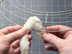 two hands are working on some kind of wire structure that is being made out of yarn