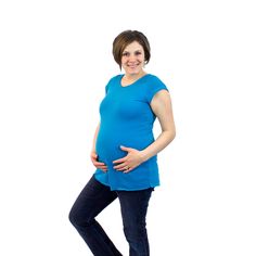 a pregnant woman standing with her hands on her stomach and smiling at the camera, against a white background