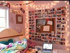 a bedroom decorated in pink and white with pictures on the wall, lights strung over the bed