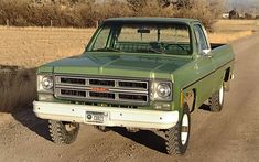 an old pick up truck parked on the side of a dirt road