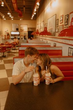 a man and woman sitting at a table in a fast food restaurant with two drinks