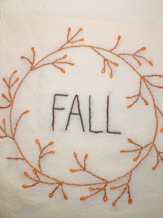 the word fall is written in orange thread on a white towel with an orange border