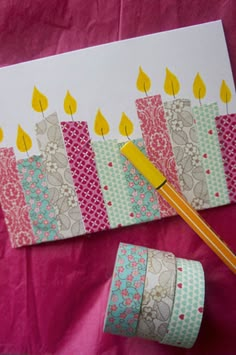 a birthday card with candles on it next to rolls of washi tape and a pencil