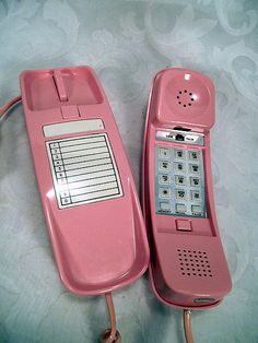 two pink telephones sitting next to each other on a white tablecloth covered surface