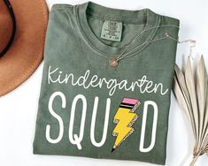 Embrace the new school year with style and comfort in our Comfort Colors® Kindergarten Teacher Squad Shirt! This tee is perfect for kindergarten teachers who want to start the school year on a high note with their crew. Made from high-quality fabric, this shirt ensures you stay comfortable while spreading cheer and positivity. Product Description for shirt: ⇝ Comfort Colors® brand shirt ⇝ Garment-dyed, 100% cotton (vintage look) ⇝ Unisex adult sizing ⇝ Props used in photos are NOT included with Colors Kindergarten, Happy First Day Of School, First Day Of School Shirt, Photo Care, Kindergarten Shirts, Squad Shirt, Kindergarten Teacher, Kindergarten Teachers, Comfort Color