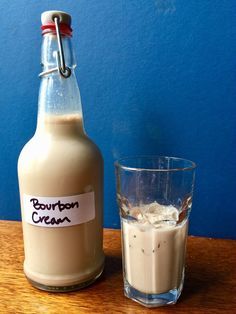 a bottle of bourbon cream next to a glass with ice and cinnamon on the table