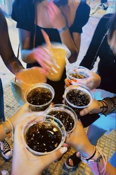 several people are holding their hands together and reaching for something in small bowls on the table