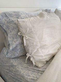 two pillows on top of a bed with white sheets and blue patterned pillowcases