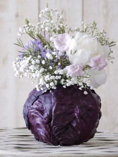 a purple vase filled with white flowers on top of a table