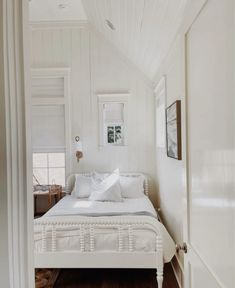 a bedroom with white walls and wood floors