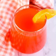 an orange drink with a slice of lemon on the rim