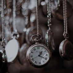 an old pocket watch hanging from chains in front of many other watches and necklaces