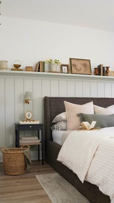 a bed with pillows and blankets on top of it next to a shelf filled with pictures