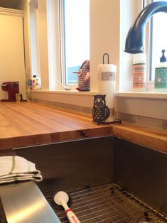 a kitchen sink under a window next to a counter with a toothbrush and soap dispenser on it