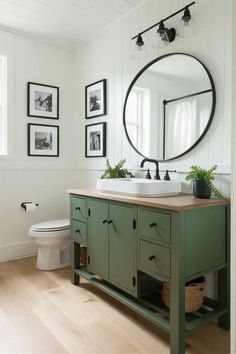 a bathroom with white walls and green cabinetry in the center, along with pictures on the wall