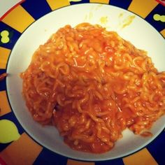 a white plate topped with noodles on top of a blue and yellow striped table cloth